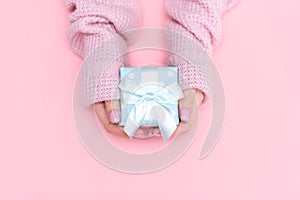 White gift box with red bow in the children`s hands on pink background