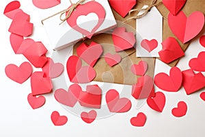 White gift box with red label in a heart form, gift wrapped in brown craft paper, tied with twine with a bow, envelope