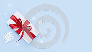 White gift box with red ribbon on blue frosty background
