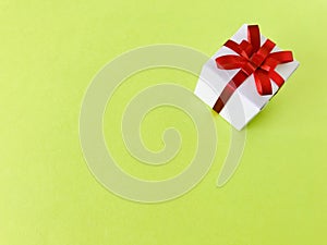 White gift box red ribbon bow on green background. copy space.