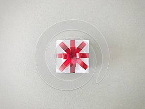 White gift box red ribbon bow on grey background , aerial view.