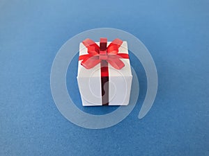 White gift box red ribbon bow on navy blue background.