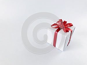 White gift box red ribbon bow on white background, copy space.