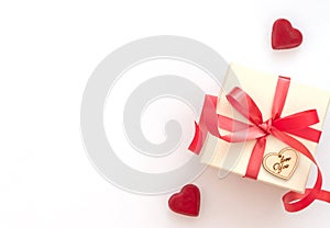 White gift box with red ribbon on white background with two sweet red hearts. Valentine`s Day concept. Valentine greeting card.