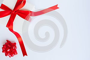 White gift box with red satin bow and ribbon on white background