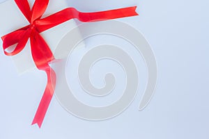 White gift box with red satin bow and ribbon on white background