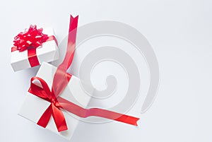 White gift box with red satin bow and ribbon on white background