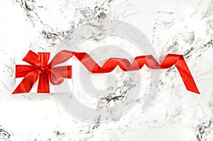 White gift box red satin ribbon bow marble background