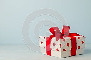 White gift box with red star pattern and red ribbon bow