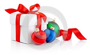 White gift box tied red ribbon bow and Christmas colored baubles Isolated on white background