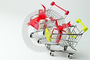 White gift box tied with red ribbon in two shopping carts