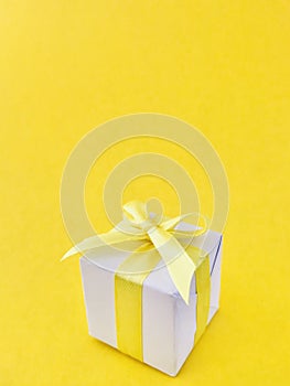 White gift box on yellow background, vertical.