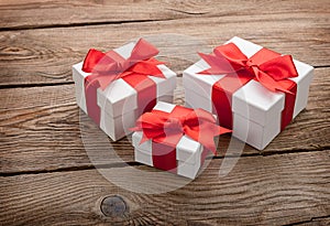 White gift boxes with red bows on the old board. gift concept