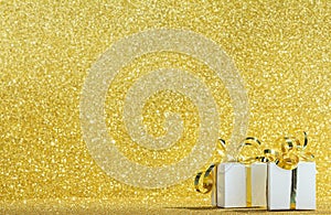White gift boxes with ribbon on sparkling gold glitter background