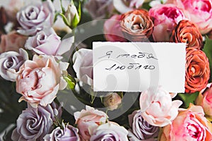 gift card with the inscription I love you in Russian in a bouquet of bright beautiful multi-colored roses