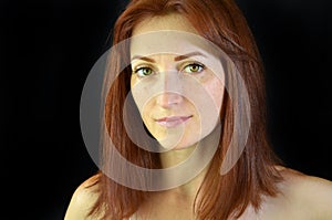 White girl with red hair and green eyes with eyelash extensions on black background looking forward