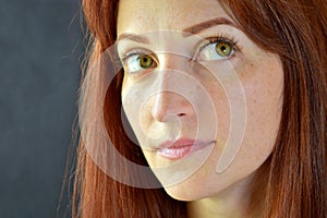 White girl with red hair and green eyes with eyelash extensions on a dark background looking up left