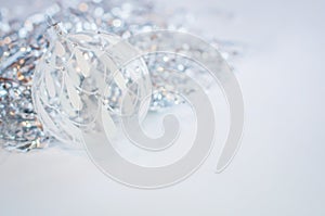 White glass decoration ball on a white background with silver tinsel behind