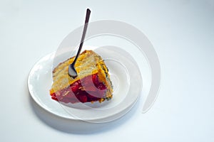 White glass plate with a piece of cake with strawberries, a spoon stuck on top.On a white isolate, place for the inscription.