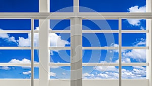 White glass window and sunshade battens with blurred white cloud in blue sky background, view from inside of building