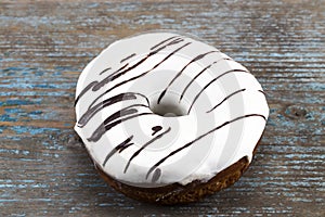 White glazed donut with chocolate stripes on wooden background photo