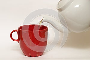 White glazed faience tea pot and red cup photo