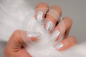 White glittered nails on gray background