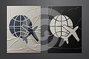 White Globe with flying plane icon isolated on crumpled paper background. Airplane fly around the planet earth. Aircraft