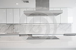 White glossy Kitchen with cooktop in Island and vent