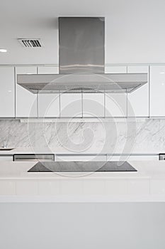 White glossy Kitchen with cooktop in Island and vent