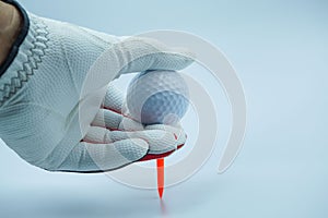 White glove hands are holding a golf ball with a white background