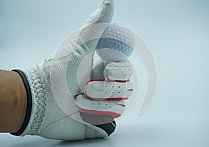 White glove hands are holding a golf ball with a white background