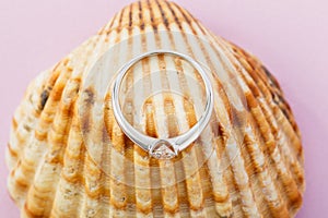 White gold engagement ring with diamond on seashell background