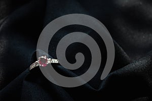 White gold ruby and diamond ring  on black fabric background