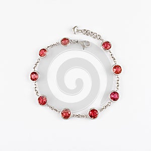 White gold or silver bracelet with red ruby gemstone on light background.