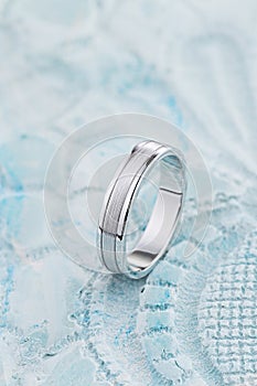 White gold wedding ring with with glossy and matte surface on pastel blue background