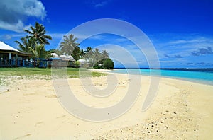 White golden sand and coral blue sea waters with Polynesian beachfront houses- beach fales, Manase, Samoa, Savai`i