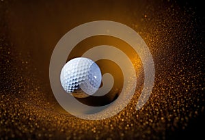 White golf ball in golden dry sand explosion on black background