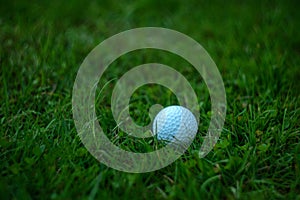 A white Golf ball on a green lawn, a place for text