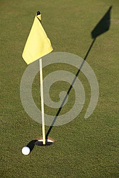 White golf ball near hole flag