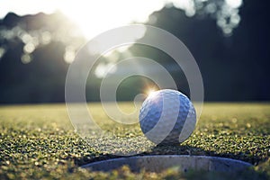 White golf ball near hole on green grass