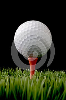 A white golf ball on a tee on black