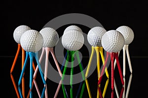 White golf balls and different colored tees