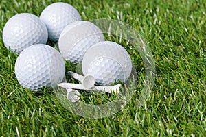 White golf balls lie on a heap of green grass