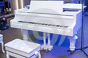 white grand piano and bench in the stage
