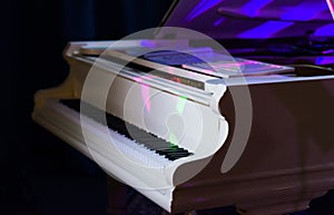 White grand piano illuminated by colored spotlights.