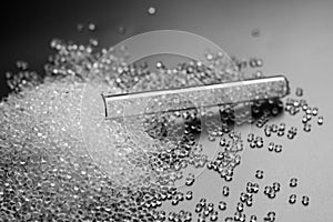 White granules of rubber and polypropylene on a black background in a chemical test tube. Plastics and polymers industry.