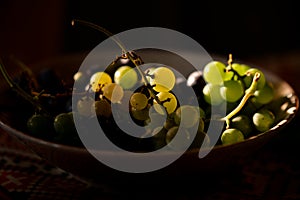 White grapes on the plate in the sun. Vitis vinifera fruits