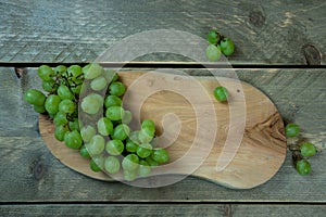 White grapes on a wooden plate. Plate is on a wooden background.