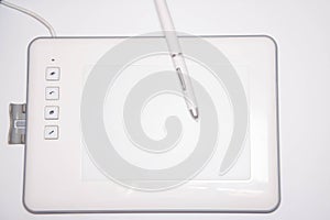 White graphics tablet on a white background. The work of a graphic designer. View of the top, side view. Tablet in macro. Pen
